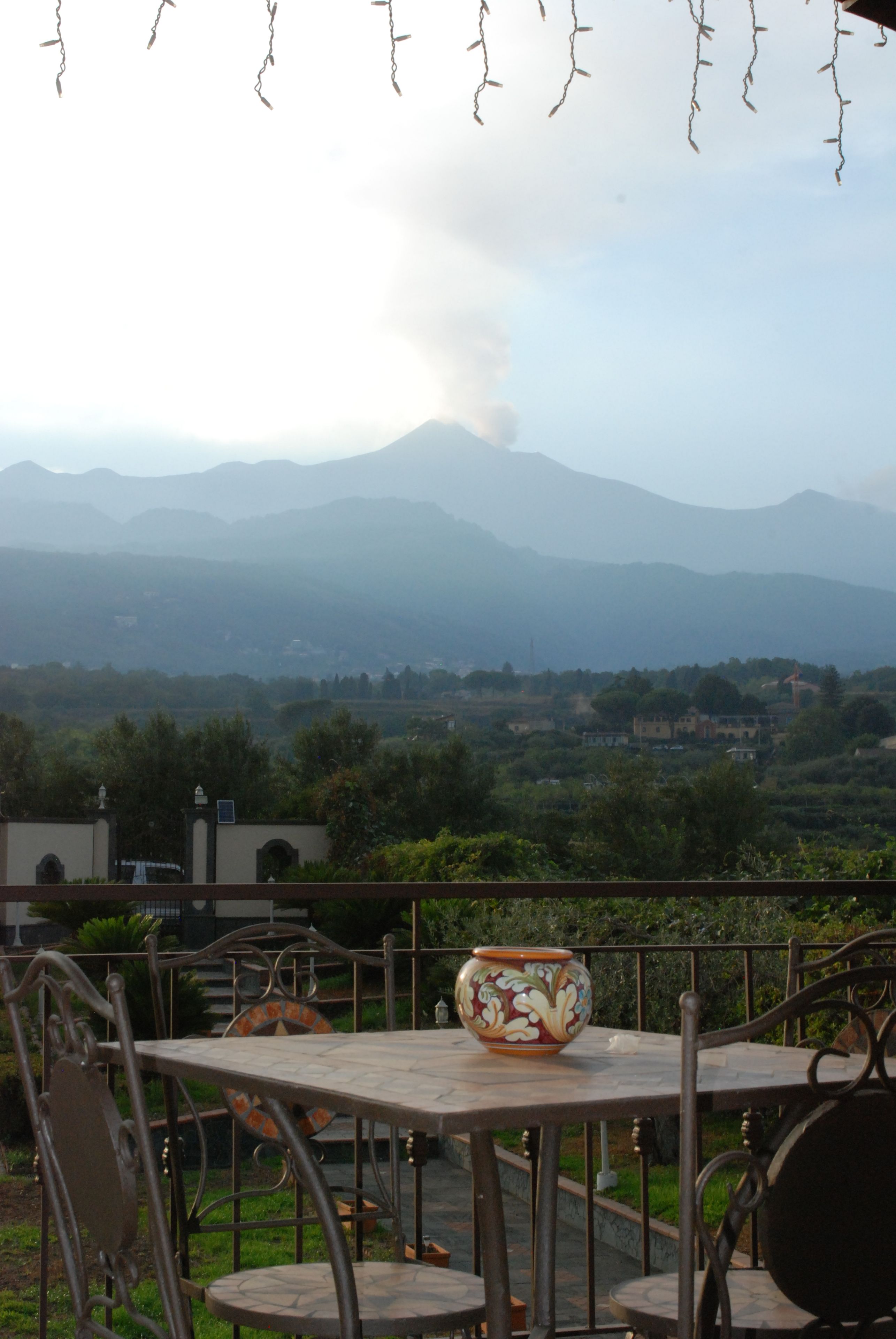 Une terrasse avec des sièges extérieurs et une vue sur les montagnes lointaines.