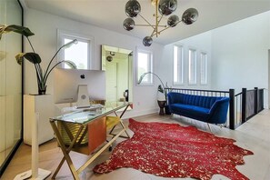 Ein modernes Wohnzimmer mit einem Glastisch, einem blauen Sofa, einem roten Teppich und einem einzigartigen Chandelier.