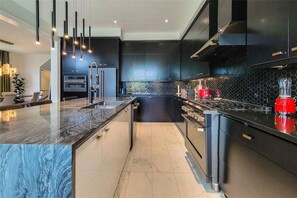Een moderne keuken met een marmeren aanrechtblad, zwarte keukenkastjes en een rode blender.