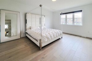 Ein Schlafzimmer mit einem Himmelbett, einem großen Spiegel und einem Fenster mit Blick auf Gebäude.