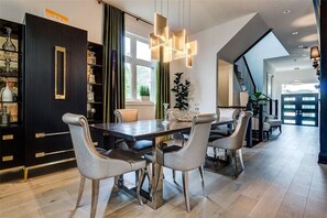 Een moderne eethoek met een kast van donker hout, een eettafel met stoelen en een trap naar een hoger gelegen verdieping.