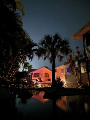 Ein Anwesen am Strand mit Pool, Palmen und einem Haus mit Balkon.