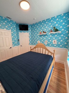 A bedroom with a bed, white doors, a mounted TV, and a wall with cloud patterns. - Unique Home Gated Community Heated Pool 5 miles to Disney (Kissimmee)
