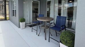 Un espace extérieur abrité, avec une table et des chaises, un ventilateur de plafond et des plantes en pot.