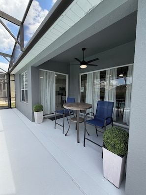 A covered outdoor seating area with a table and chairs, a ceiling fan, and potted plants. - Unique Home Gated Community Heated Pool 5 miles to Disney (Kissimmee)