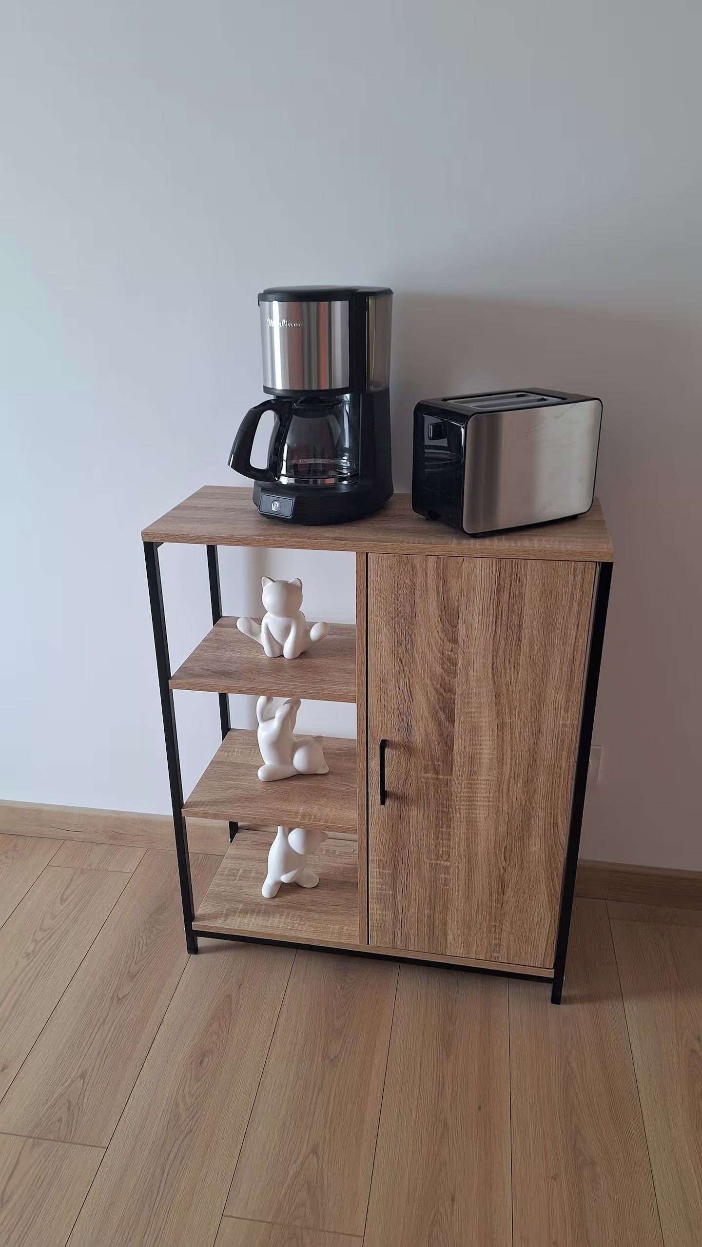 Ein Holzkabinet mit Kaffeemaschine und Toaster darauf.
