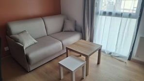 Una sala de estar con sofá, una mesa de centro y una ventana con cortinas.