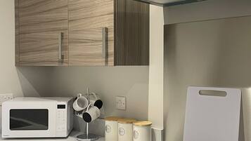 A modern kitchen with a built-in microwave, a stovetop with a glass cooktop, wooden cabinets, and a stainless steel range hood.