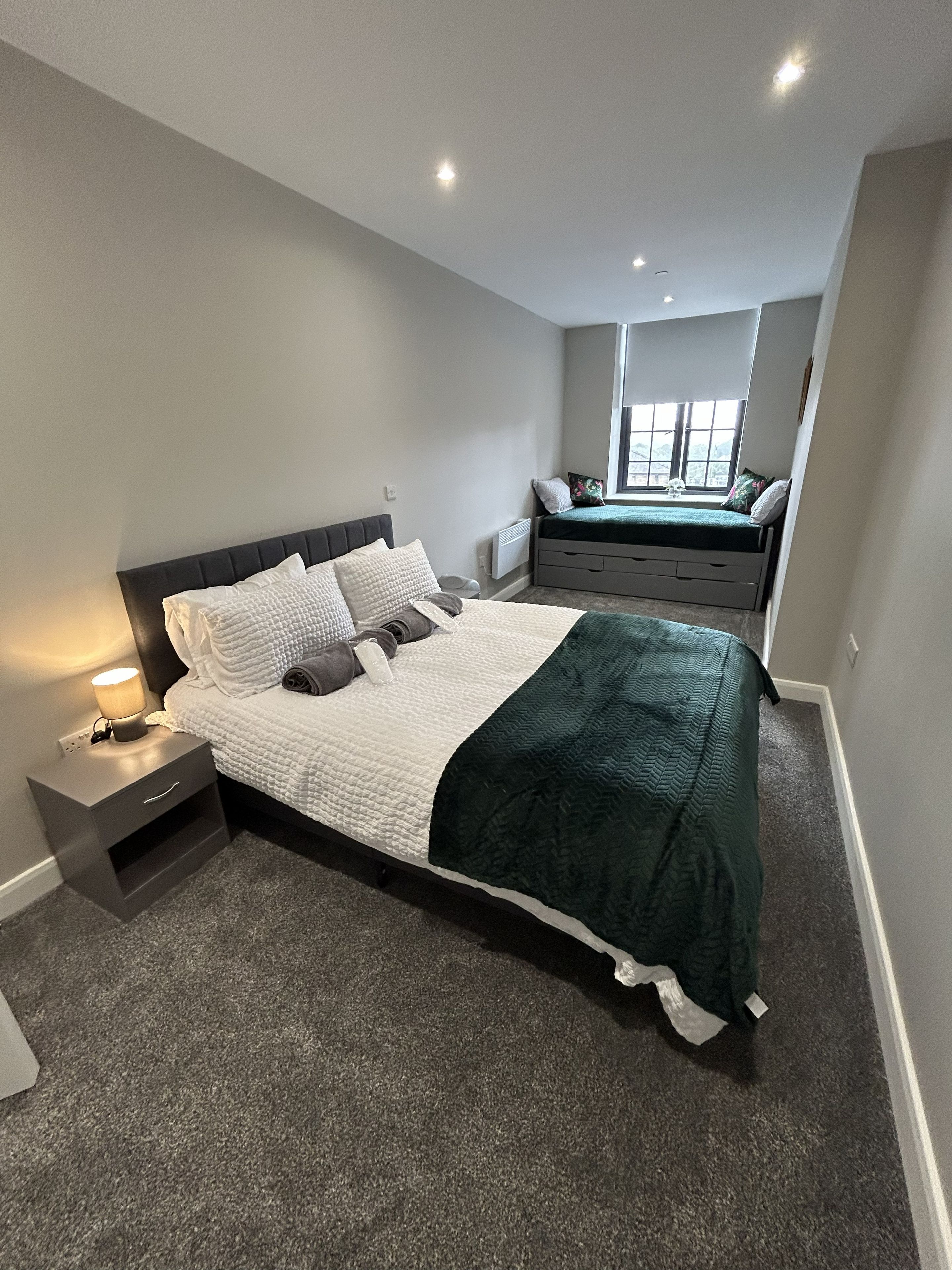Een slaapkamer met een bed, nachtkastje en een raam.