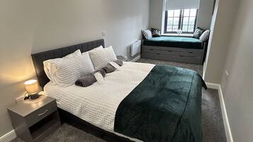 Een slaapkamer met een bed, nachtkastje en een raam.