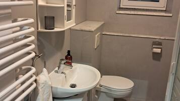 Une salle de bain avec un lavabo blanc, des toilettes et un porte-serviettes.