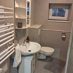 Une salle de bain avec un lavabo blanc, des toilettes et un porte-serviettes.