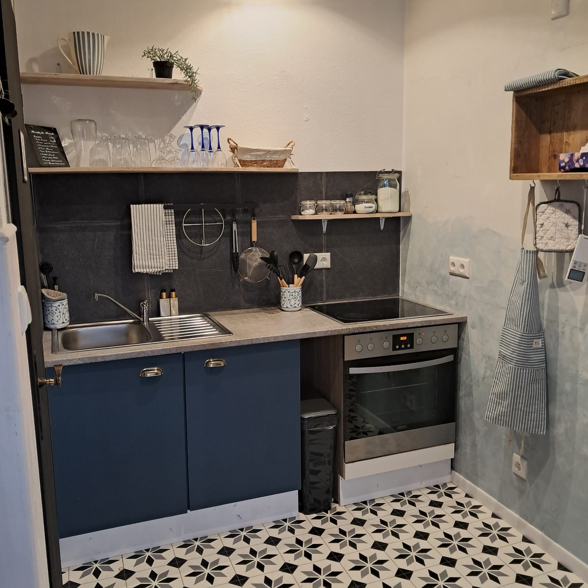 A kitchen with dark blue cabinets, a stainless steel sink, and a built-in oven.