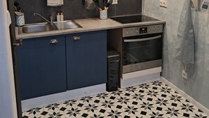 Eine Küche mit dunkelblauen Schränken, einer Edelstahl-Spüle und einem eingebauten Backofen.