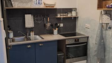 A kitchen with dark blue cabinets, a stainless steel sink, and a built-in oven.