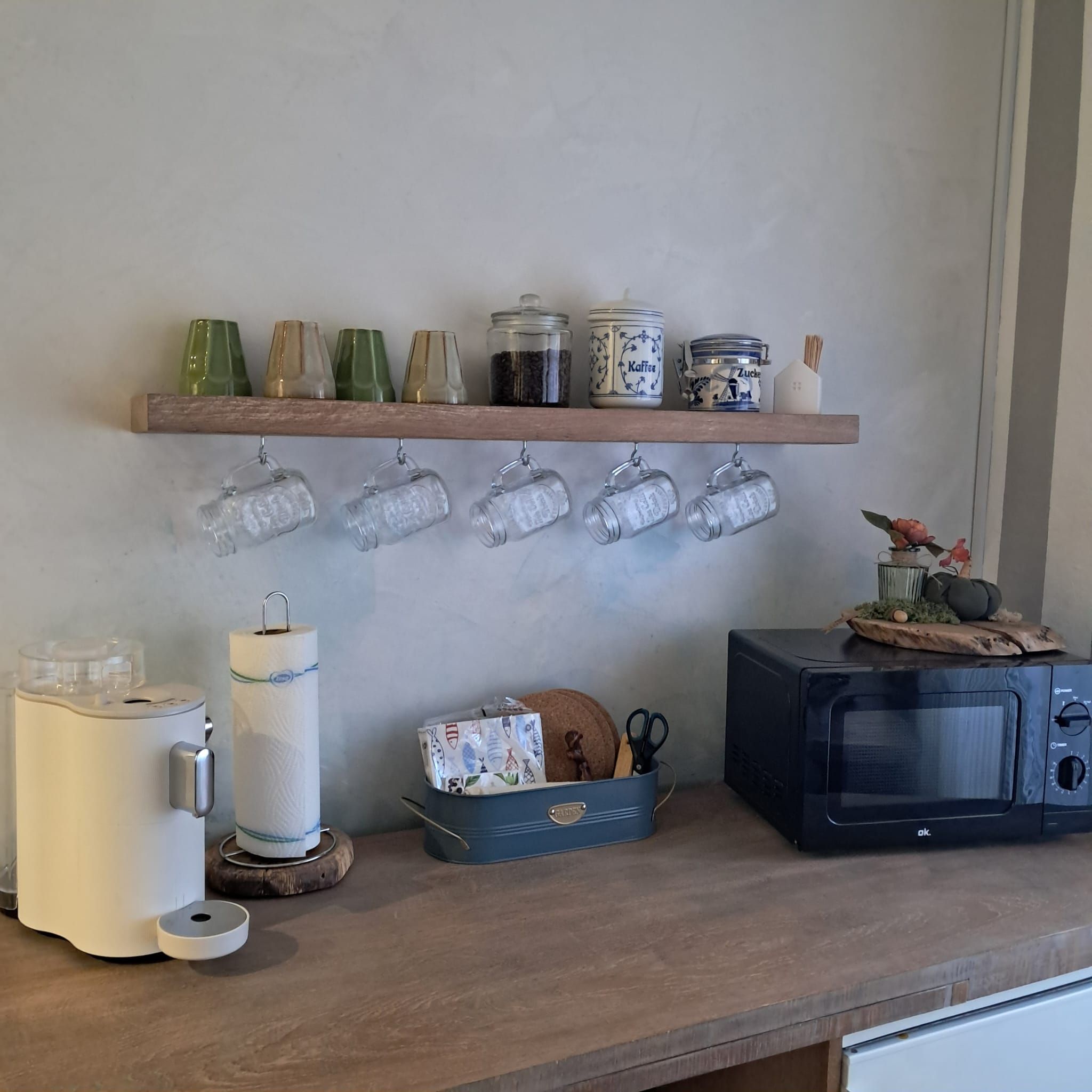 Eine Küchenarbeitsplatte mit einer Mikrowelle, einem Toaster und einem Regal mit Gläsern und Einmachgläsern.