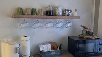 Eine Küchenarbeitsplatte mit einer Mikrowelle, einem Toaster und einem Regal mit Gläsern und Einmachgläsern.
