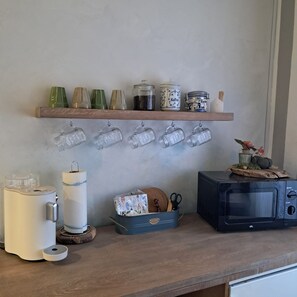 Een aanrecht met een magnetron, een broodrooster en een plank met potten en glazen.