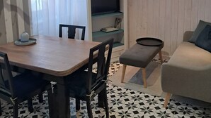 Ein Zimmer mit Esstisch, Stühlen, einer Couch, einem Fernseher und einem gemusterten Boden.