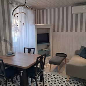 Une pièce comprenant une table à manger, des chaises, un canapé, un téléviseur et un sol à motifs.
