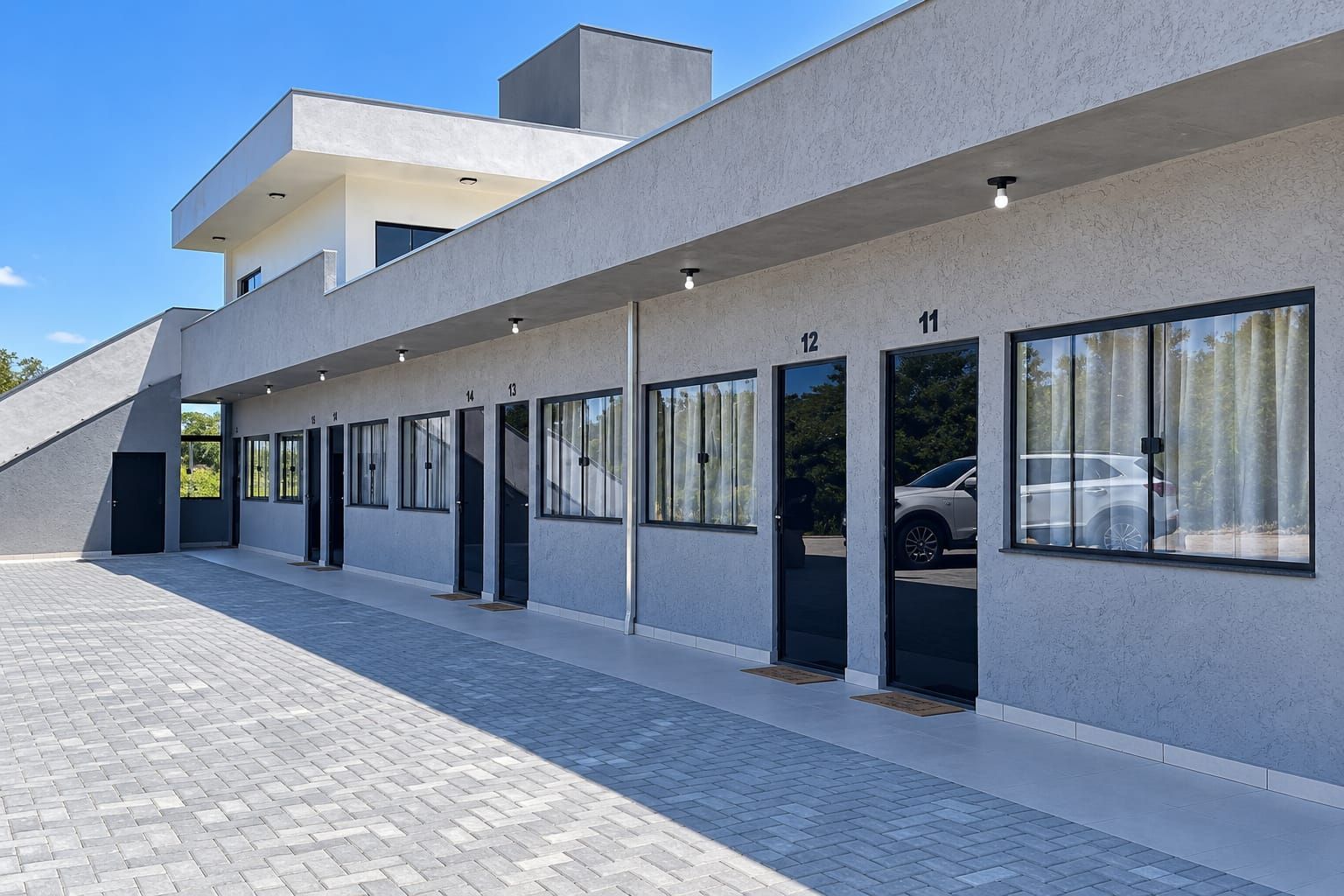 Een modern gebouw met een plat dak, grote ramen en een verharde looppad.