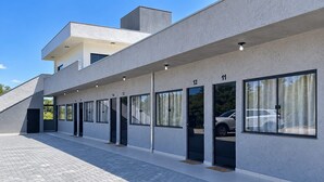 A modern building with a flat roof, large windows, and a paved walkway. - Pousada Tio Tonho (Penha)