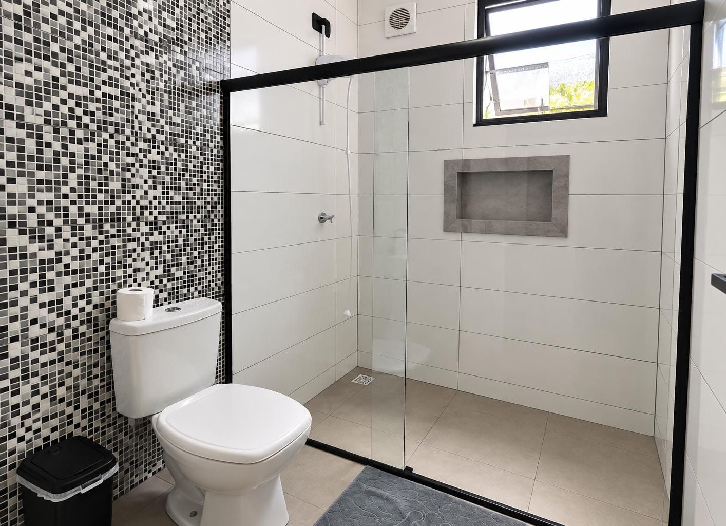 Ein modernes Badezimmer mit Toilette, Duschkabine und Wand aus Mosaikfliesen.