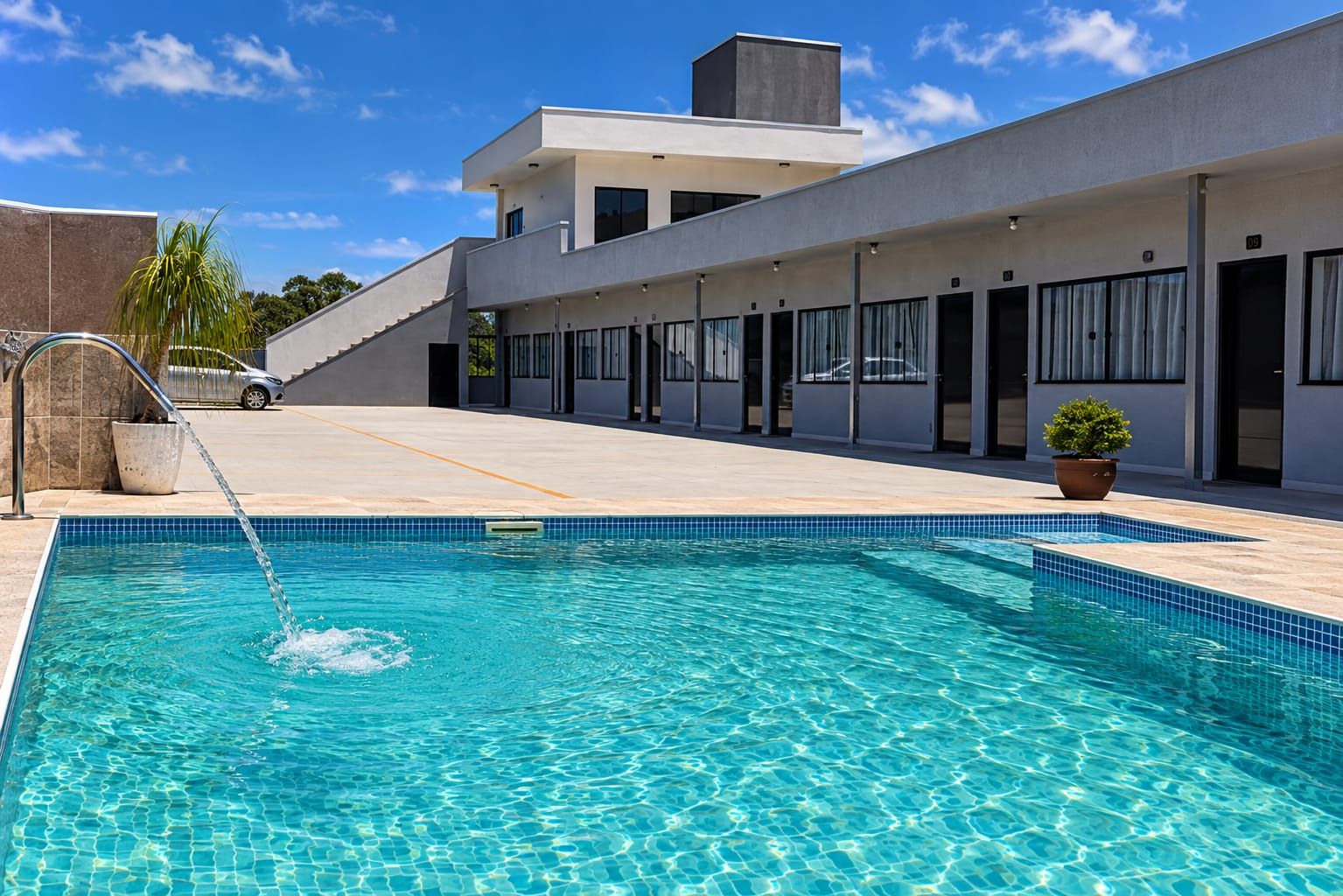 A modern hotel with a swimming pool, a covered outdoor area, and a car parked nearby.