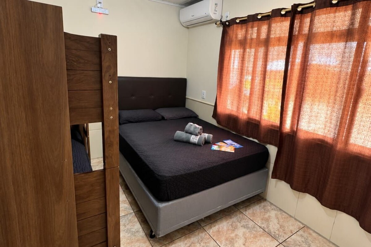 Una habitación con literas, una cama individual, aire acondicionado y una ventana con cortinas.