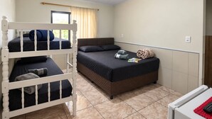 A room with a bunk bed, a single bed, and a small table with a remote control. - Pousada Tio Tonho (Penha)
