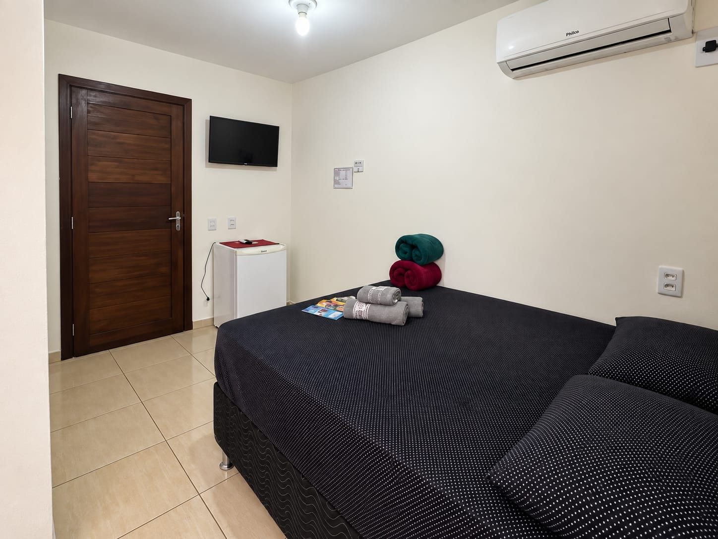 Une chambre d’hôtel équipée d’un lit, d’une télévision, d’un climatiseur et d’un mini-bar.