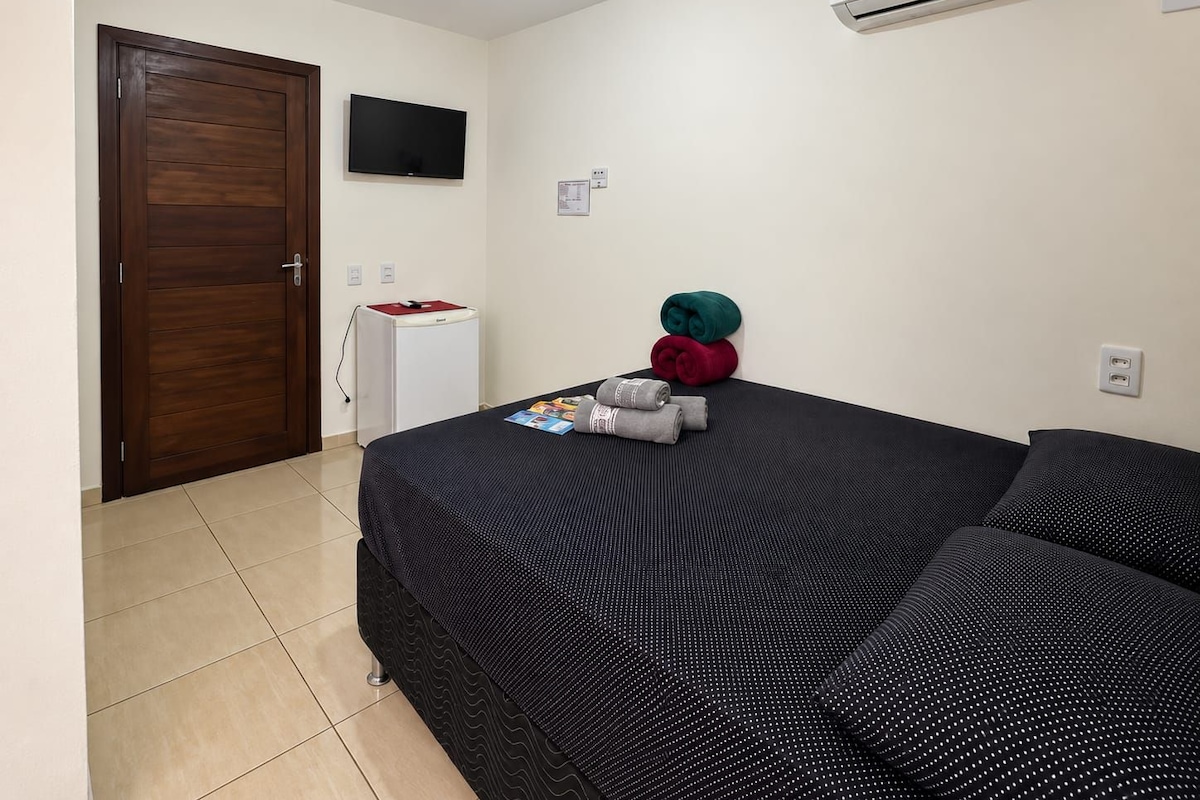 Ein Hotelzimmer mit einem Bett, einem Fernseher, einer Klimaanlage und einer Minibar.