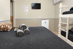 Ein Stockbett mit Fernseher darüber, ein kleiner Kühlschrank und eine Wand mit einem Sicherheitsschild.