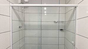 A shower enclosure with a glass door, a white ceiling, and a black floor. - Pousada Tio Tonho (Penha)