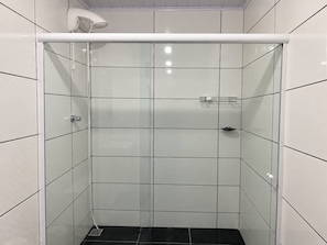 Eine Duschkabine mit Glastür, weißer Decke und schwarzem Boden.