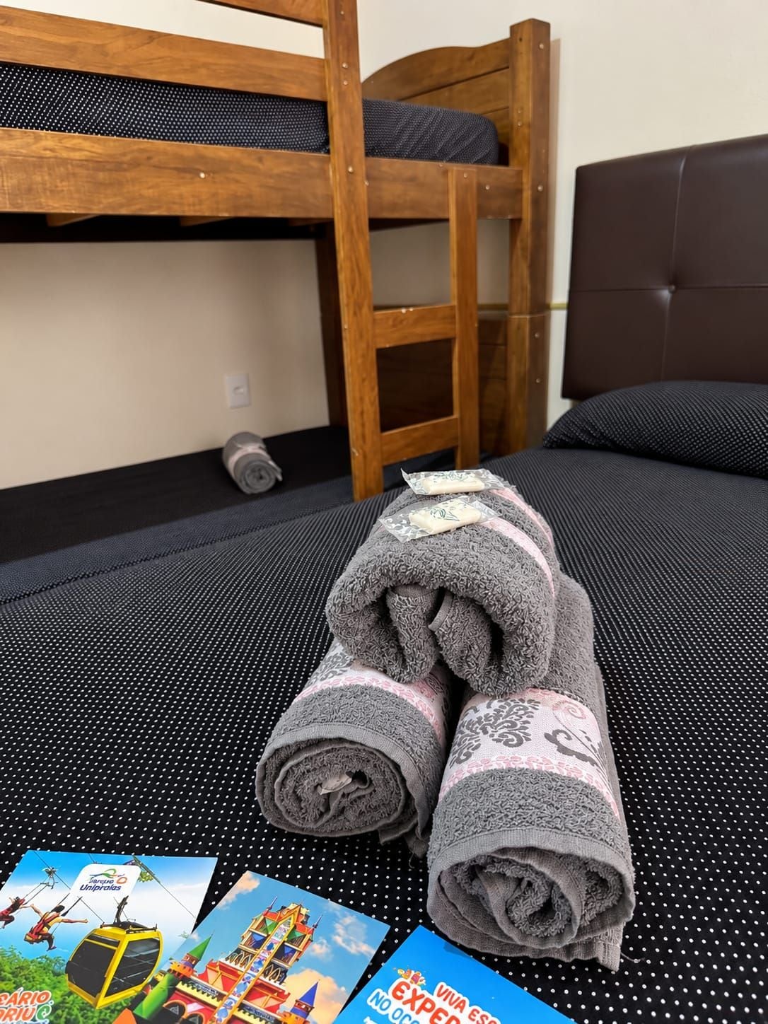 Una cama litera con estructura de madera, colchón negro y cabecero marrón.