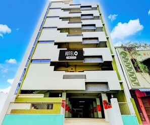 A multi-story hotel with a sign reading 'HOTELO' and 'OYO-Serviced'. - Super Deluxe Room (Tirupati)