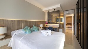 A hotel room with a large bed, a desk, a mirror, and a bathroom visible through an open door. - Vrbo Property (Almería)