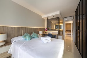 Ein Hotelzimmer mit einem großen Bett, einem Schreibtisch, einem Spiegel und einem durchgehenden Tür zugehörigen Badezimmer.