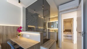 A modern hotel room with a wooden desk, a glass partition, and a bed with a white headboard. - Vrbo Property (Almería)