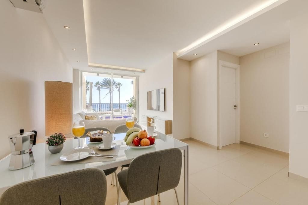 A modern dining area with a glass table, chairs, and breakfast items.