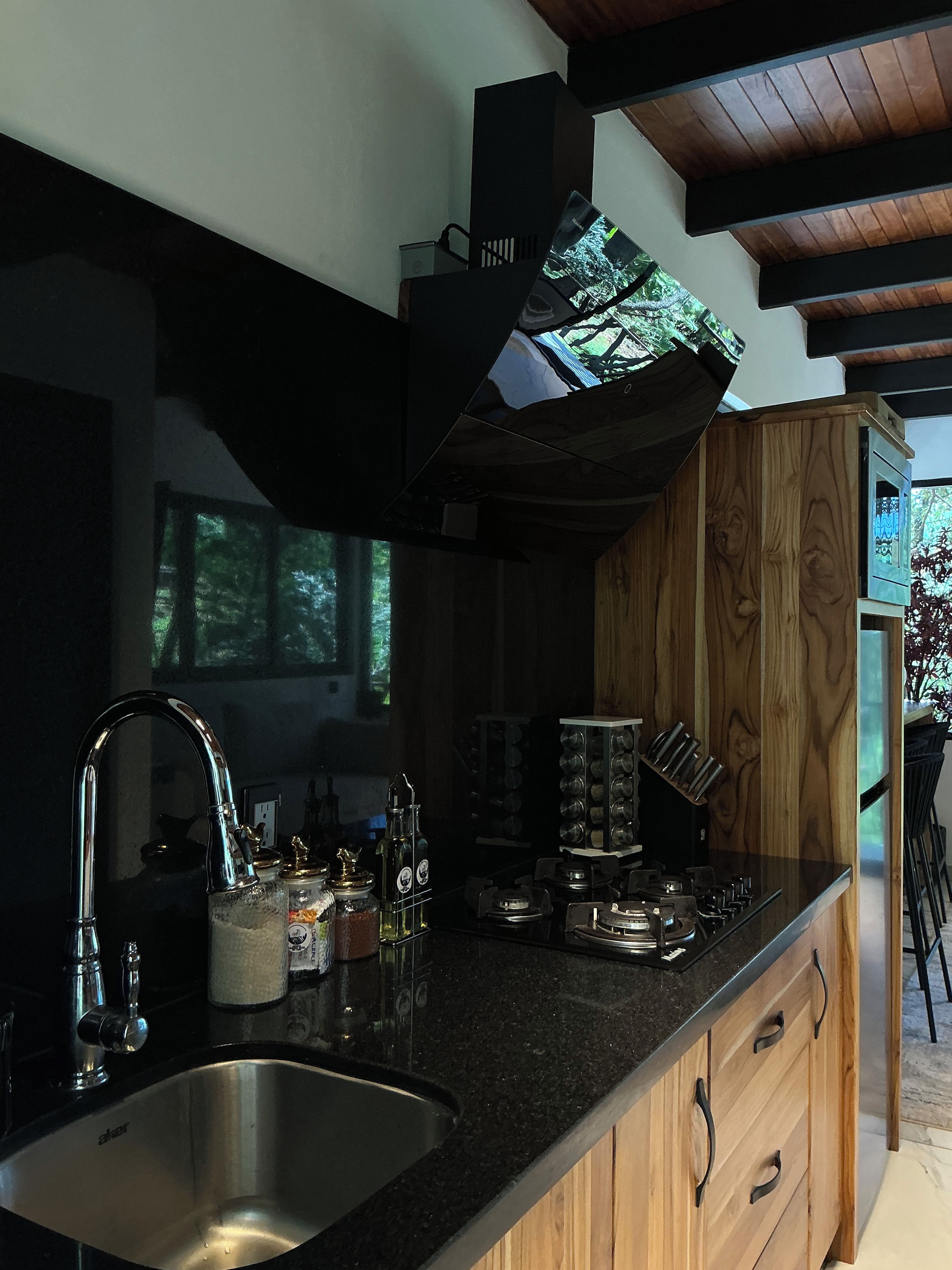 A modern kitchen with a stainless steel sink, wooden cabinets, and a built-in range hood.