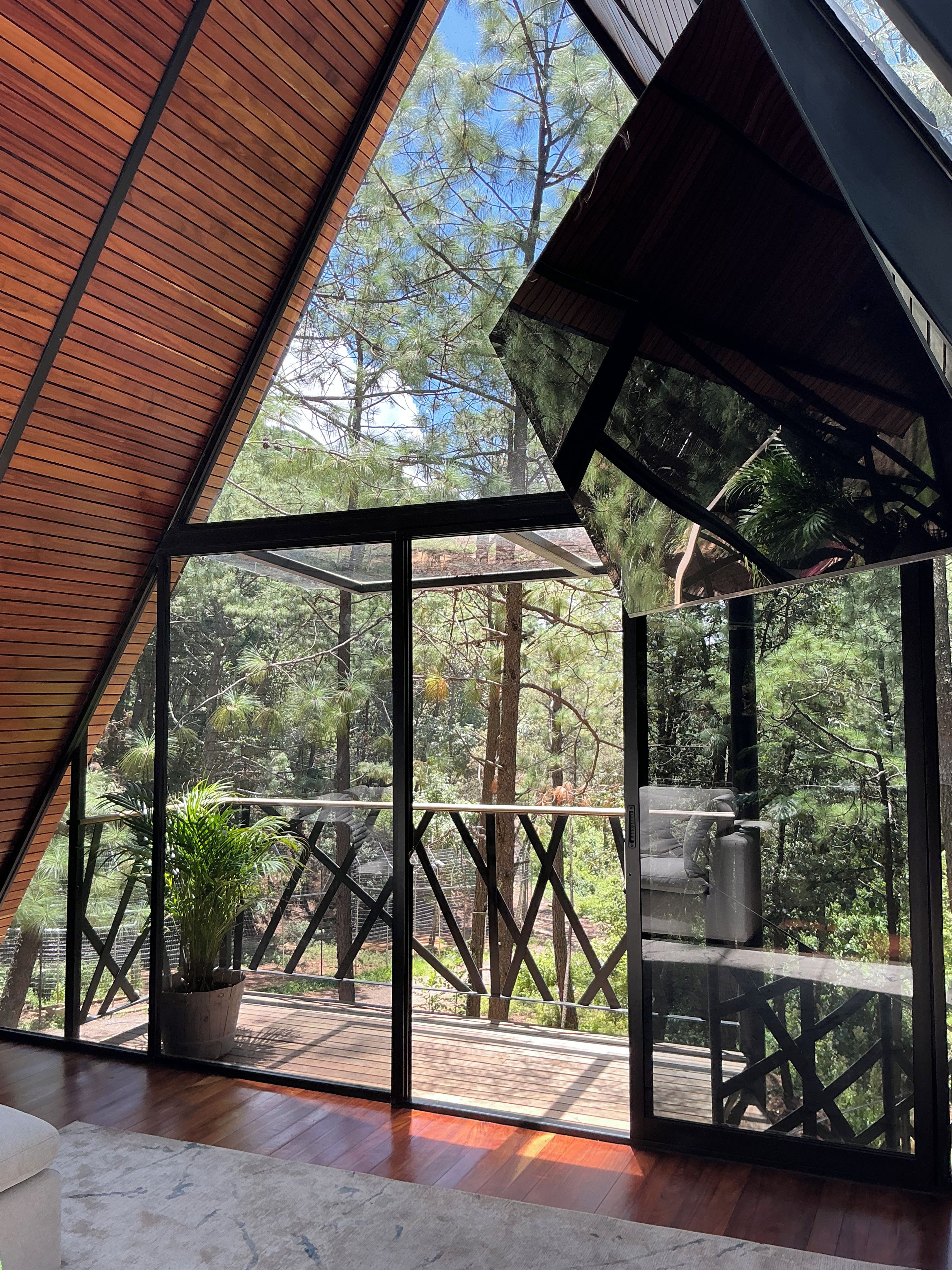 Un intérieur moderne avec une grande baie vitrée donnant sur une terrasse en bois et un espace extérieur.