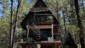 Una cabaña con fachada de madera, un balcón y una escalera en espiral.