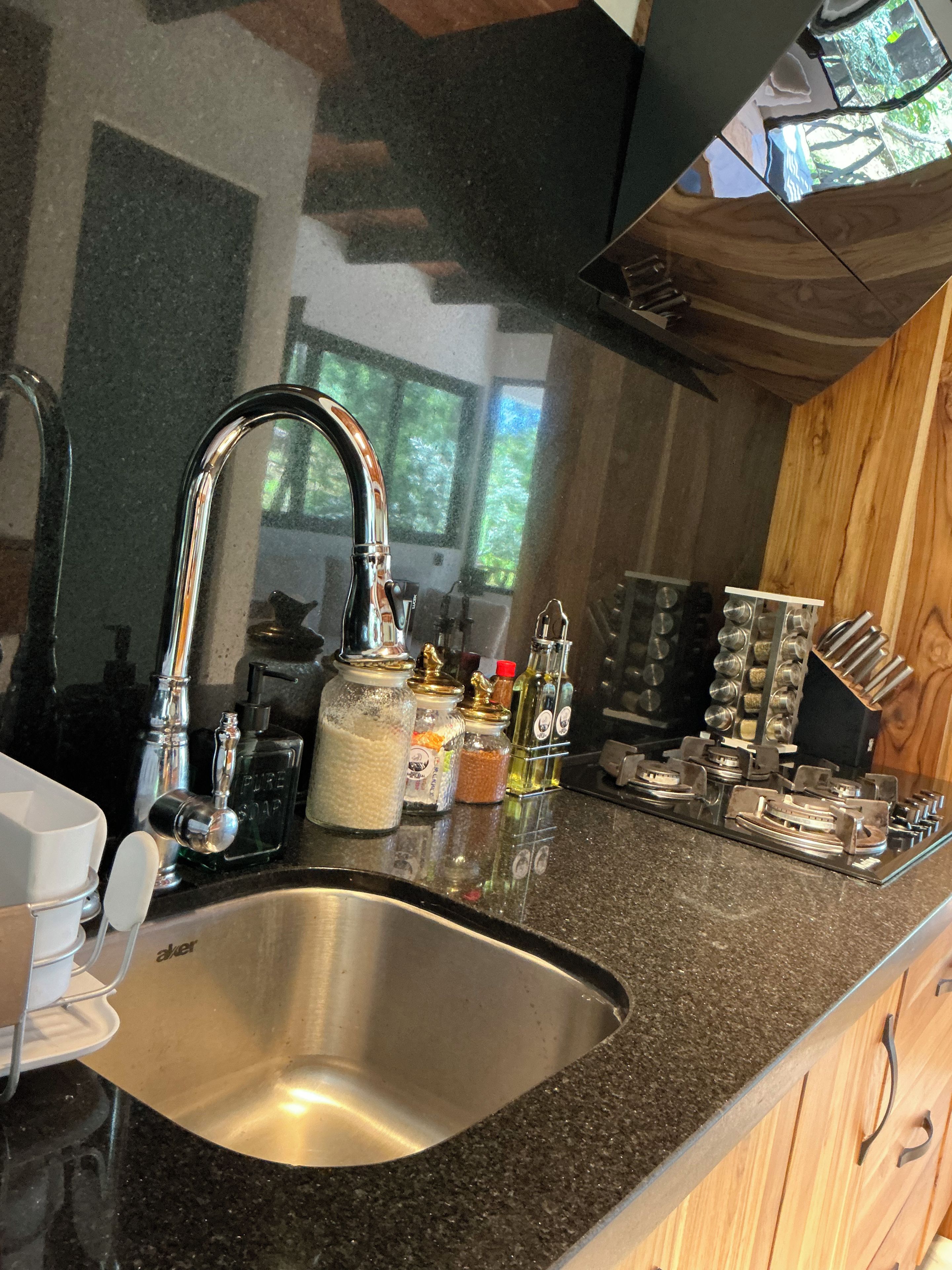 Una cocina con un lavamanos de acero inoxidable, un grifo moderno y distintos utensilios y recipientes en la encimera.