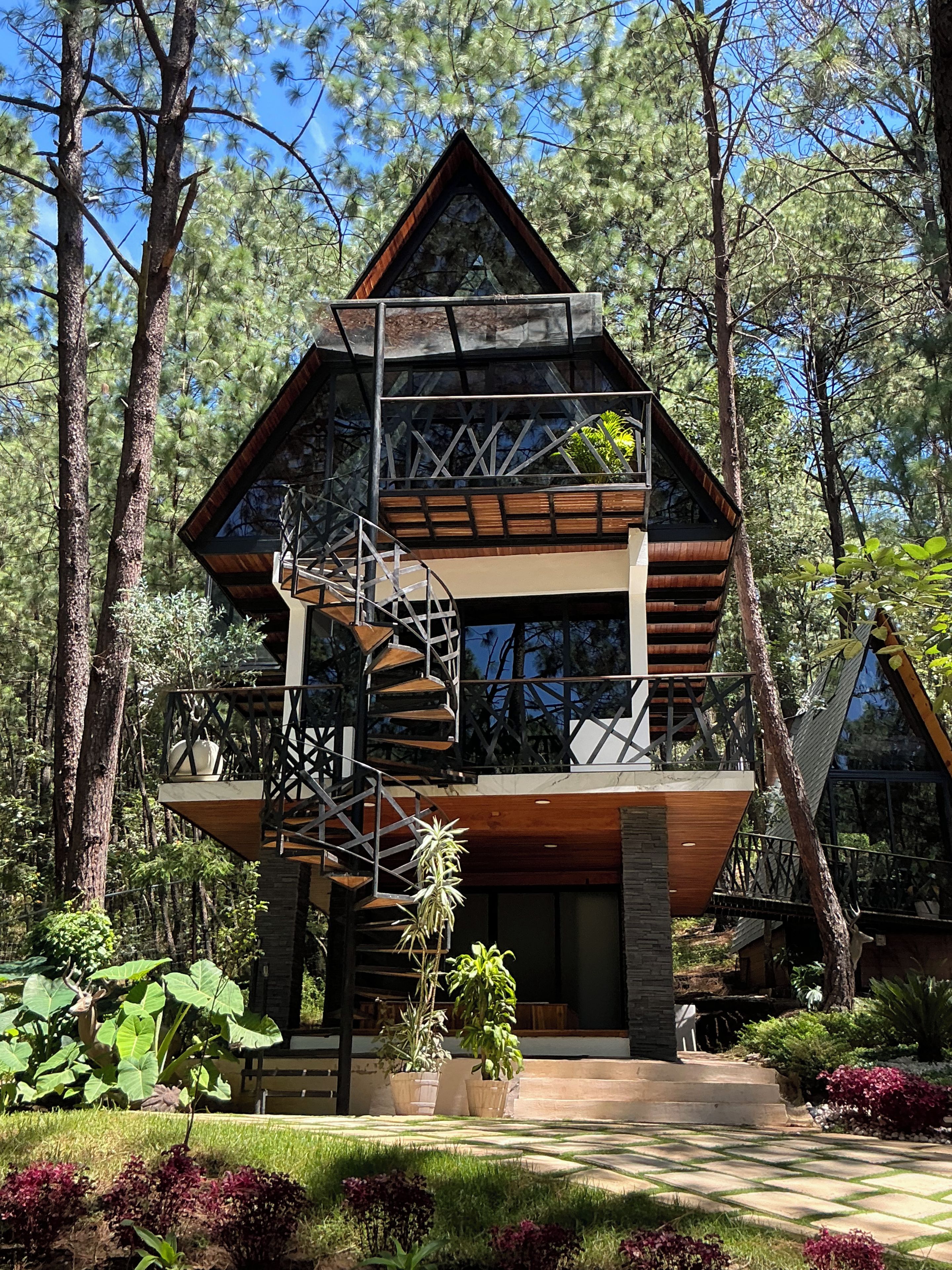 Une cabane à deux étages, avec une façade en bois, un balcon et un escalier en colimaçon.