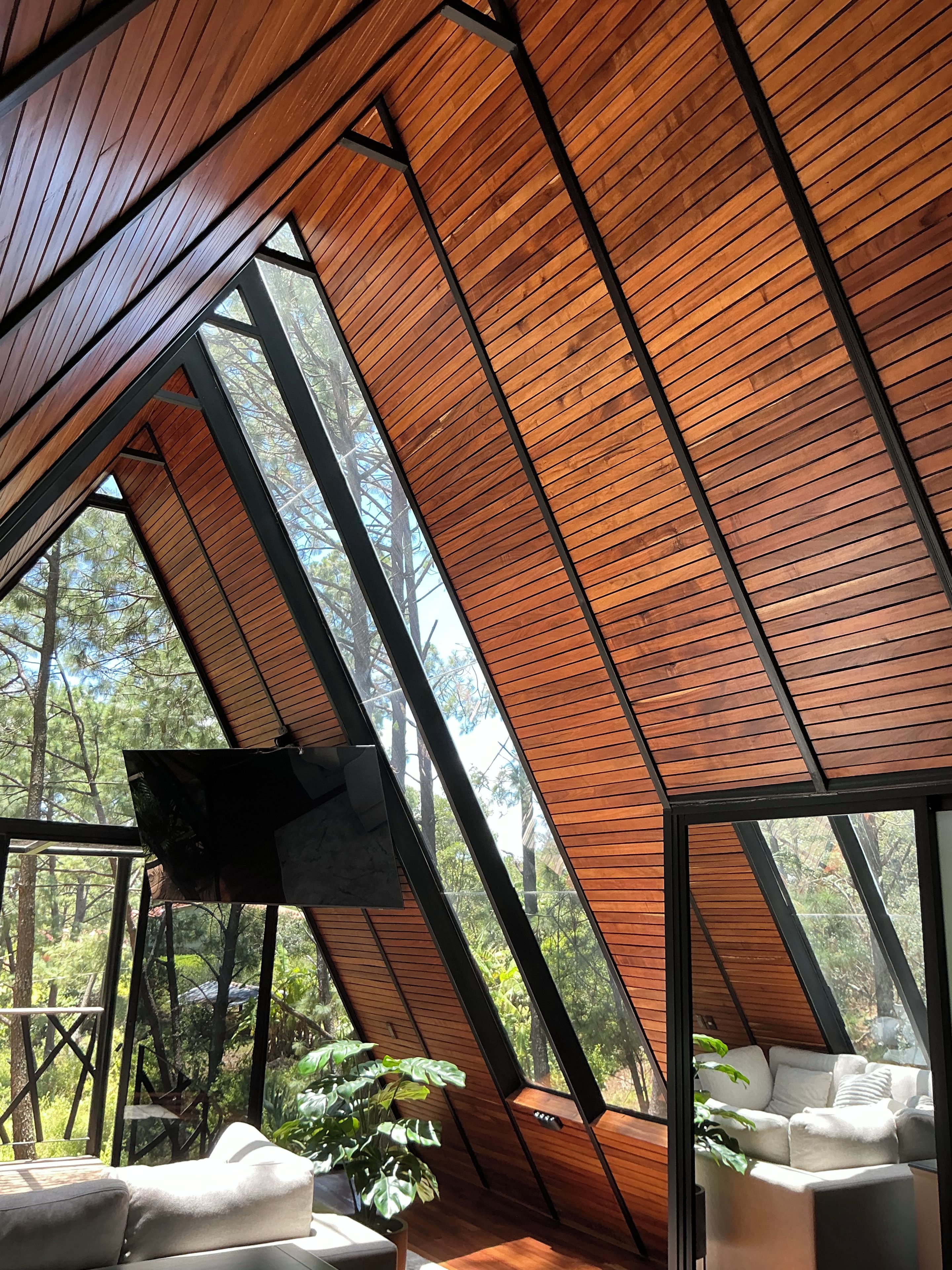 Un interior moderno con techo inclinado, ventanas grandes y un rincón de estar con cojines.