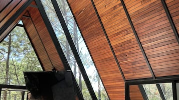 Un interior moderno con techo inclinado, ventanas grandes y un rincón de estar con cojines.