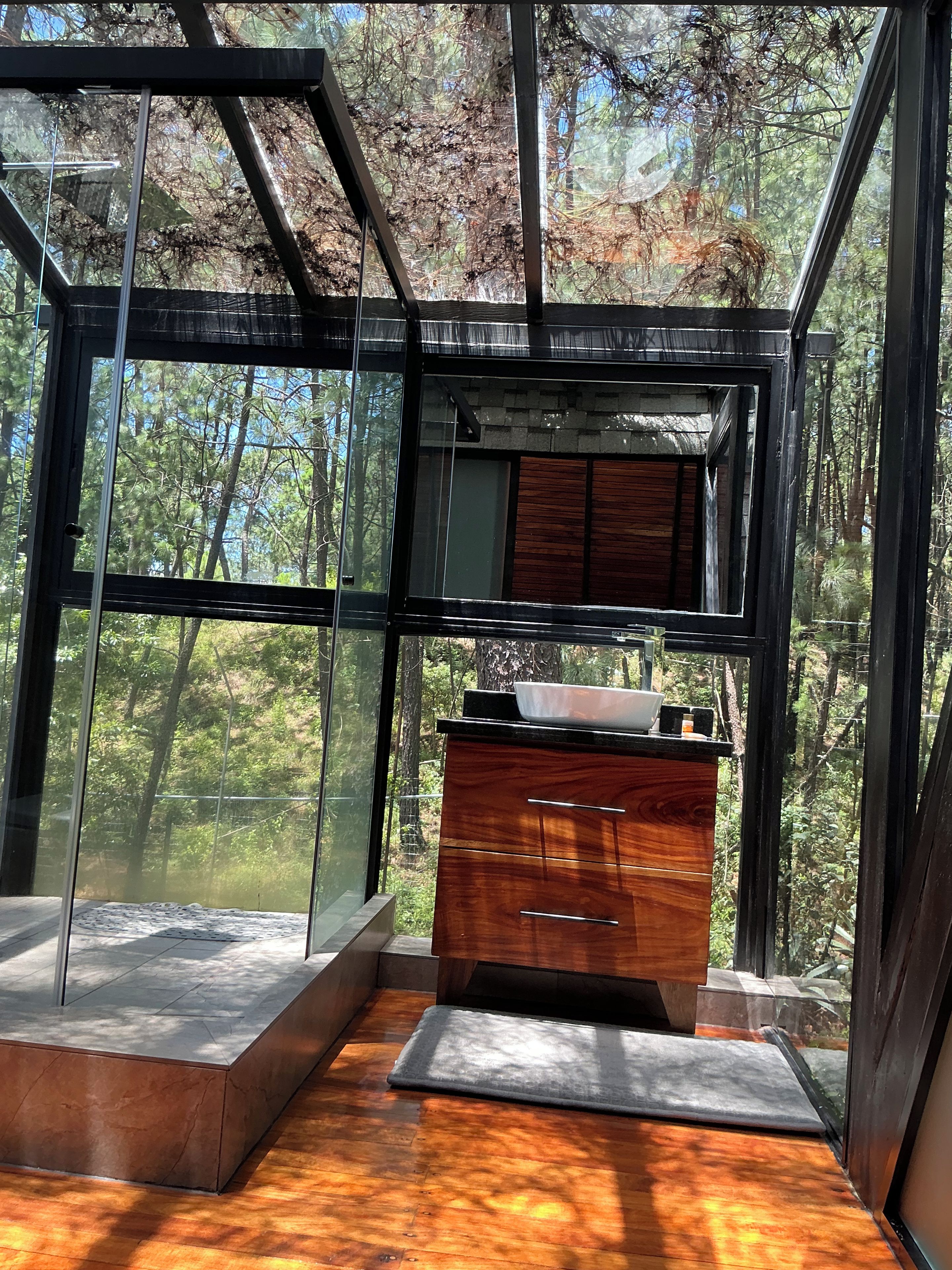 Un interior moderno con un armario de madera y una pared de vidrio que ofrece vistas a un bosque.
