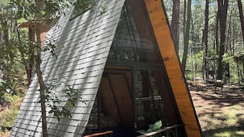 A small cabin with a sloped roof, a wooden deck, and a glass door.